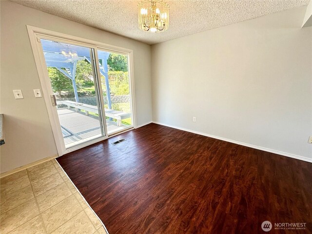 spare room featuring an inviting chandelier, baseboards, a textured ceiling, and visible vents