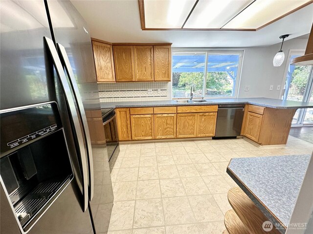 kitchen with backsplash, stainless steel refrigerator with ice dispenser, brown cabinets, a sink, and black dishwasher