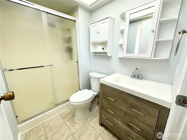 bathroom with vanity, a shower stall, and toilet