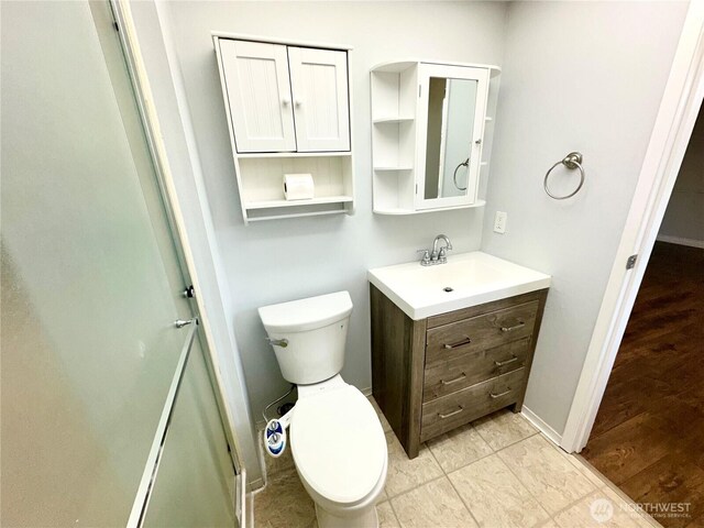 bathroom featuring toilet, baseboards, and vanity