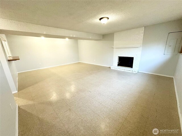 finished below grade area with tile patterned floors, baseboards, a fireplace, and a textured ceiling