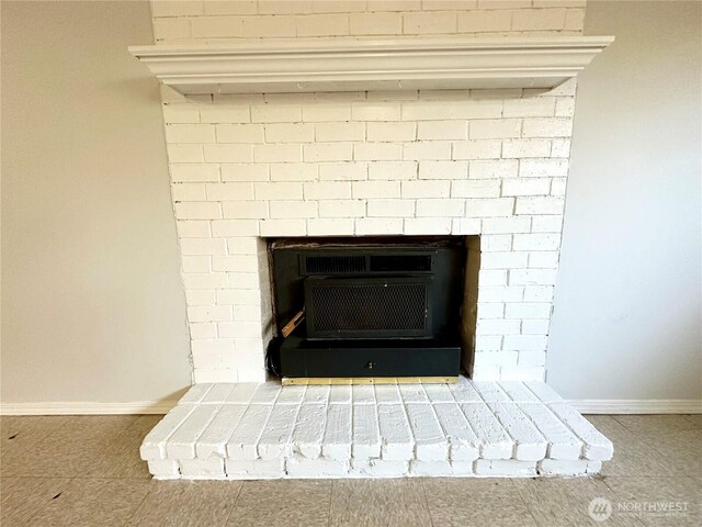 interior details with a fireplace with raised hearth, baseboards, and heating unit