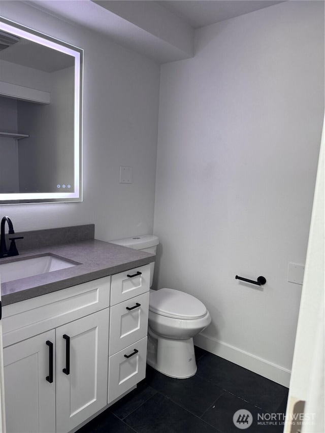half bathroom with toilet, baseboards, tile patterned flooring, and vanity