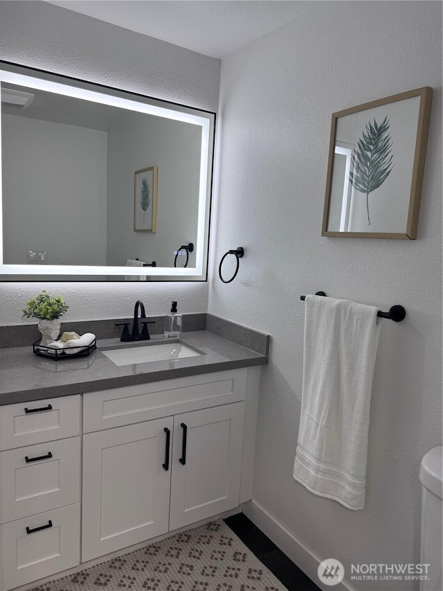 half bathroom featuring vanity, tile patterned flooring, baseboards, and toilet