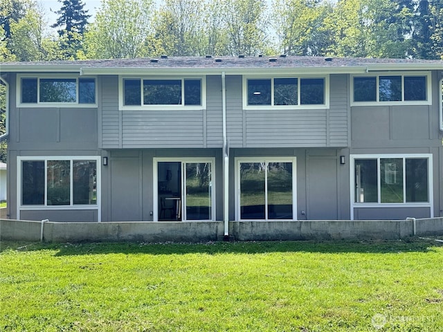 back of house featuring a shingled roof, board and batten siding, and a yard