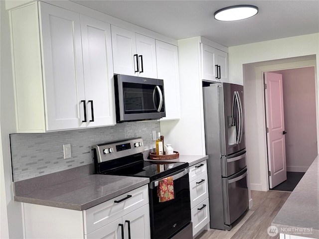 kitchen with white cabinetry, appliances with stainless steel finishes, light wood-style flooring, and tasteful backsplash