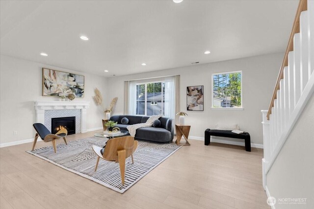 living area with stairs, recessed lighting, light wood finished floors, and a fireplace