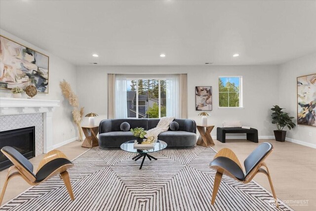living room featuring recessed lighting, baseboards, a tiled fireplace, and light wood-type flooring