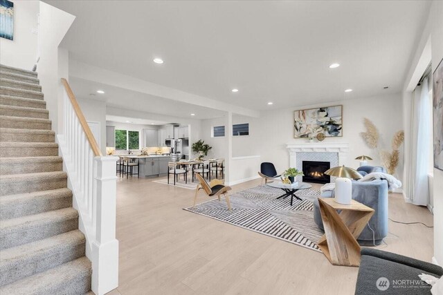 living area featuring recessed lighting, stairs, a glass covered fireplace, and light wood-type flooring