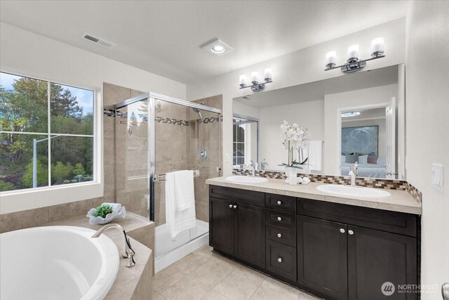 ensuite bathroom featuring visible vents, a garden tub, tile patterned floors, a sink, and a stall shower