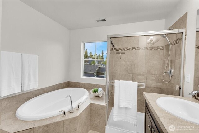 bathroom with visible vents, a shower stall, a garden tub, and vanity