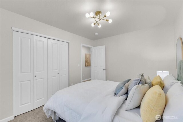 bedroom featuring light colored carpet, a chandelier, and a closet