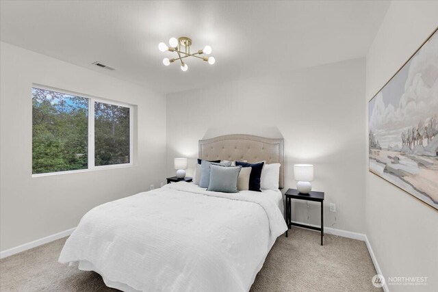 carpeted bedroom with baseboards, visible vents, and an inviting chandelier