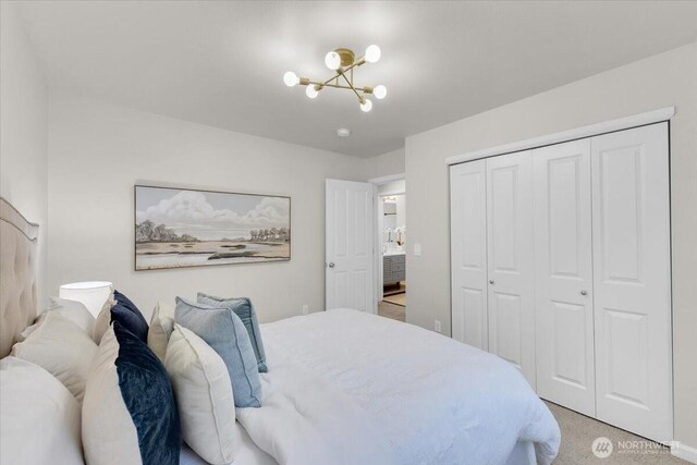 bedroom featuring an inviting chandelier, light carpet, and a closet