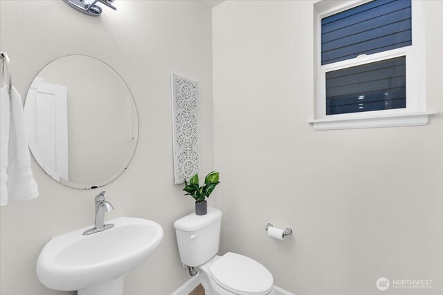 bathroom featuring baseboards, a sink, and toilet