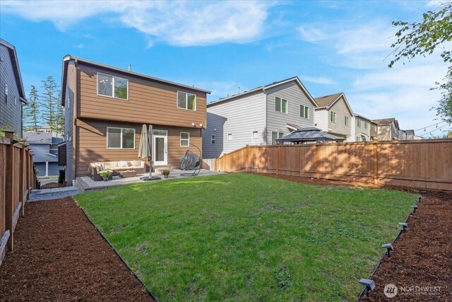 rear view of property featuring a lawn, a fenced backyard, and outdoor lounge area