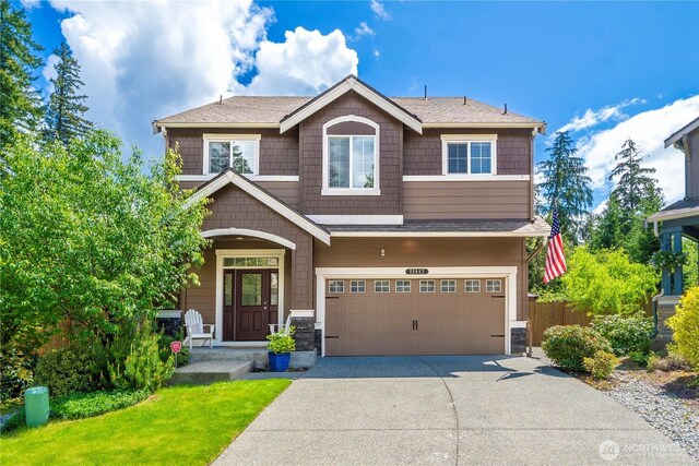 craftsman-style home featuring driveway, an attached garage, and stone siding