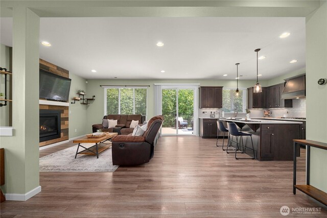 living area featuring wood finished floors, a large fireplace, recessed lighting, and baseboards