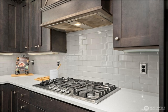 kitchen with stainless steel gas stovetop, custom exhaust hood, dark brown cabinetry, and light countertops