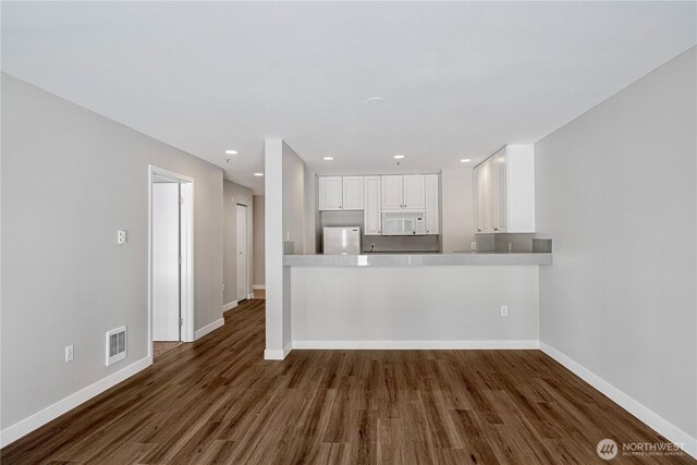 unfurnished living room featuring baseboards, dark wood-type flooring, recessed lighting, and visible vents