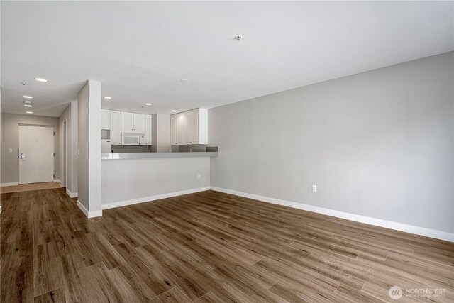 unfurnished living room featuring baseboards, recessed lighting, and wood finished floors