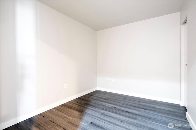 unfurnished room featuring baseboards and dark wood-style floors