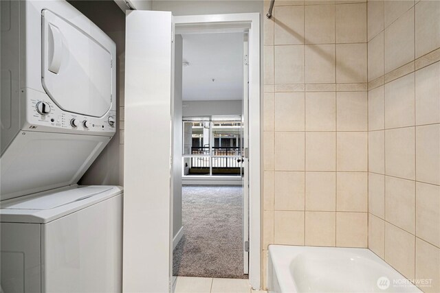 laundry area featuring laundry area, stacked washer and clothes dryer, tile patterned flooring, and carpet flooring