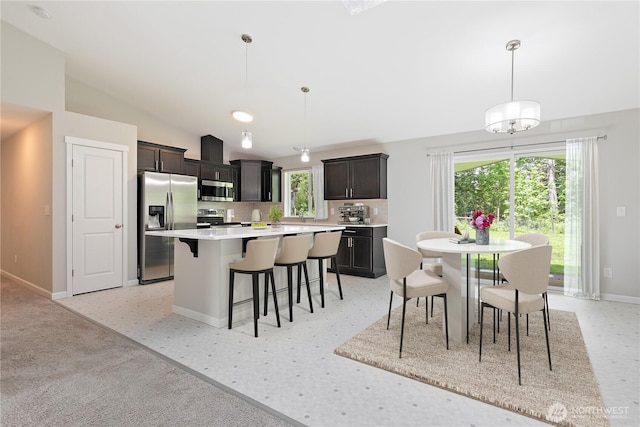 15627 240th St E, Graham, WA 98338 - kitchen with appliances with stainless steel finishes, a kitchen breakfast bar, a kitchen island, baseboards, and light countertops