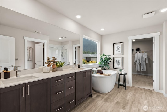 full bathroom with double vanity, a sink, a freestanding bath, and a stall shower