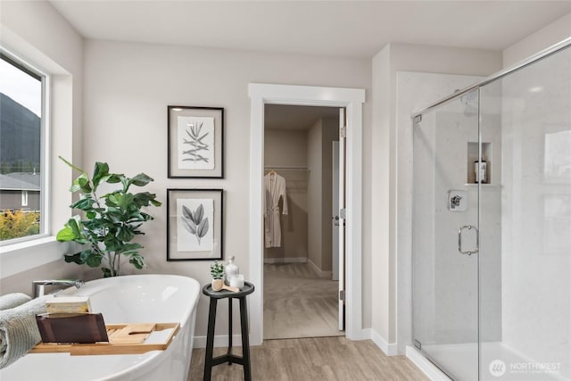 full bath featuring a soaking tub, a shower stall, and wood finished floors