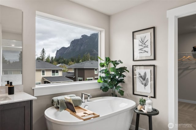 bathroom with a freestanding tub, baseboards, vanity, and a mountain view
