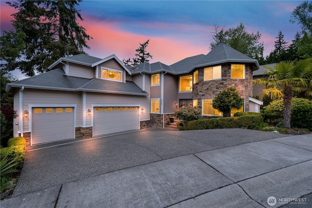view of front of house with an attached garage, aphalt driveway, and stone siding