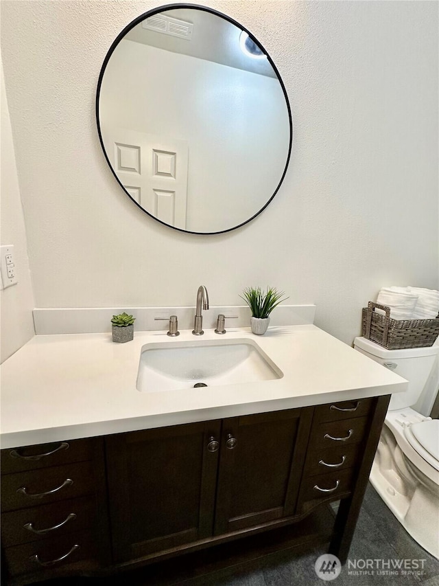 bathroom featuring toilet, visible vents, and vanity