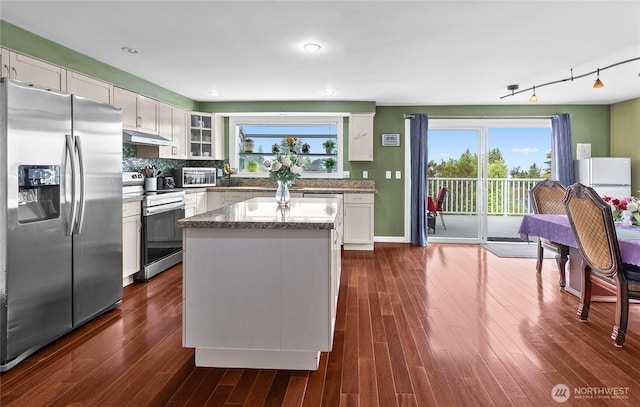 431 12th Pl N, Edmonds, WA 98020 - kitchen featuring appliances with stainless steel finishes, under cabinet range hood, a center island, dark wood-style flooring, and white cabinetry