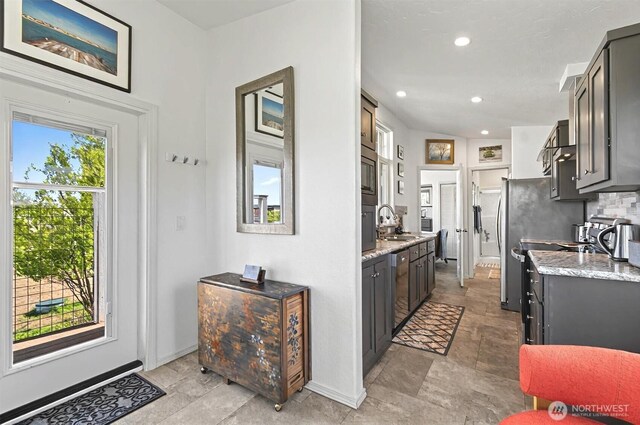kitchen featuring appliances with stainless steel finishes, a sink, recessed lighting, baseboards, and stone finish flooring