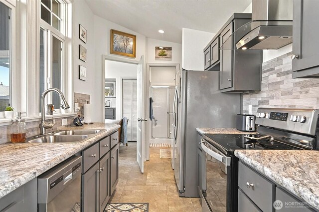 kitchen with a sink, gray cabinets, wall chimney range hood, and stainless steel appliances
