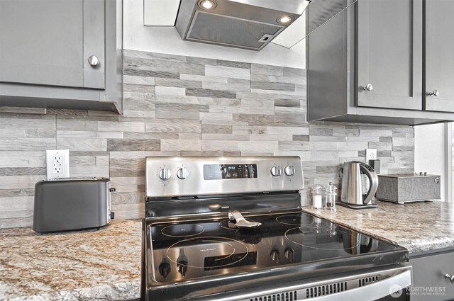 kitchen featuring light stone countertops, extractor fan, gray cabinets, tasteful backsplash, and stainless steel range with electric cooktop