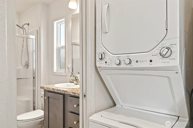 bathroom with vanity, a shower with shower door, and stacked washer / dryer