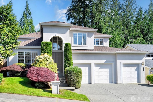 view of front of property with driveway, stucco siding, roof with shingles, and a garage