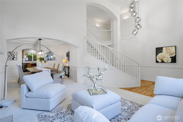 living area with arched walkways, stairs, and a towering ceiling