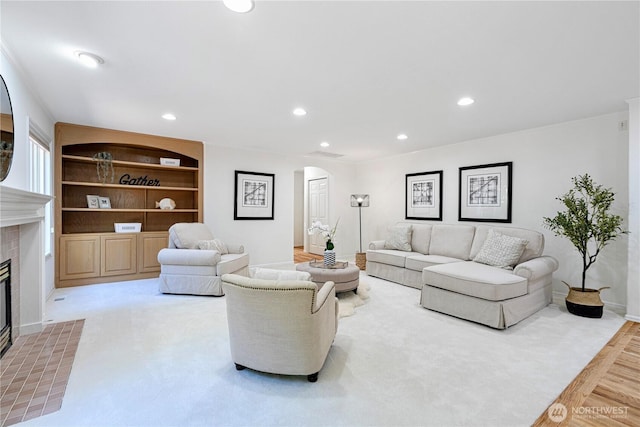 living room featuring arched walkways, a fireplace, baseboards, recessed lighting, and built in features
