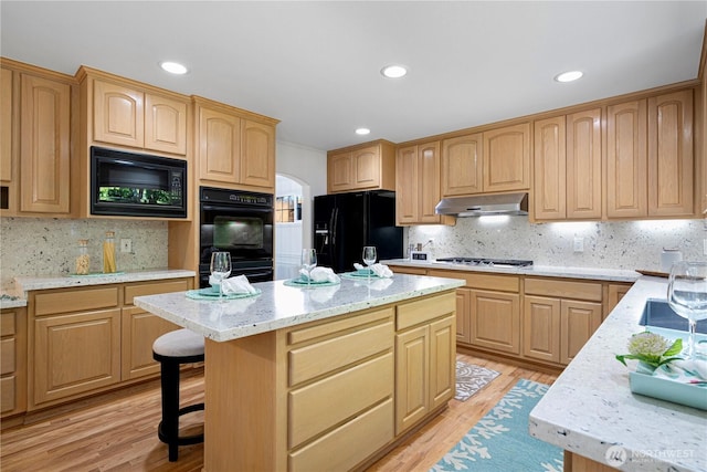 kitchen featuring black appliances, under cabinet range hood, light brown cabinets, backsplash, and recessed lighting
