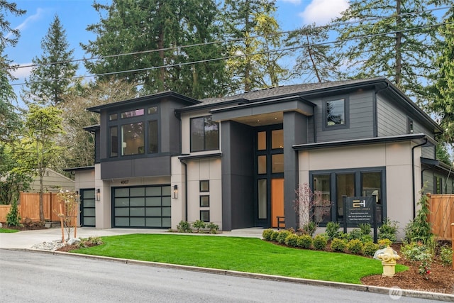 contemporary house with stucco siding, fence, driveway, and a garage