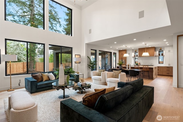 living room with a towering ceiling, recessed lighting, baseboards, and light wood-style floors