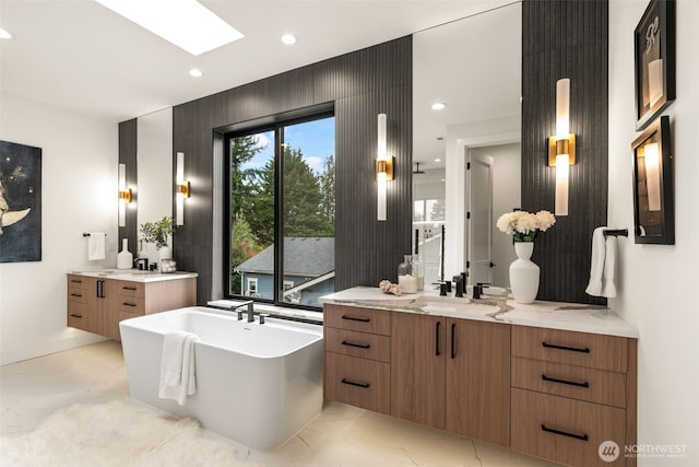 full bathroom featuring recessed lighting, a freestanding tub, two vanities, and marble finish floor