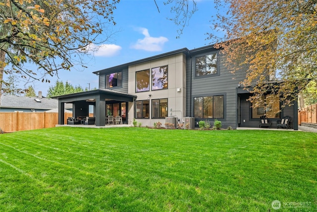 rear view of house with a lawn, a patio, and fence