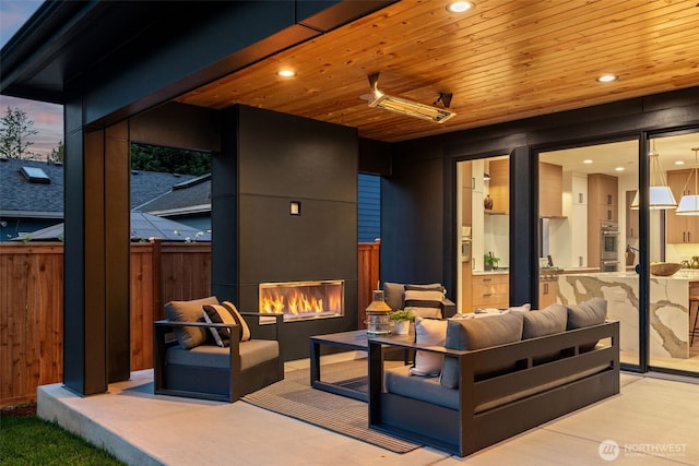 view of patio with ceiling fan, fence, and an outdoor living space with a fireplace
