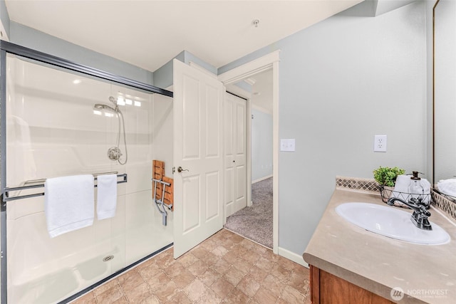 bathroom with vanity, baseboards, a shower stall, and stone finish flooring