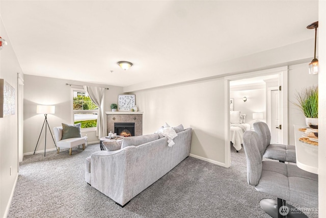 living area featuring a tiled fireplace, baseboards, and carpet
