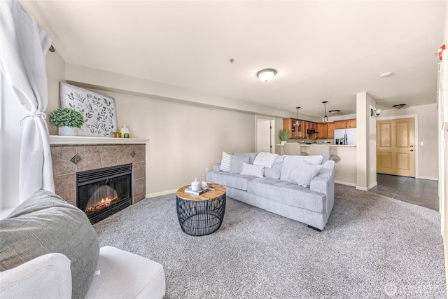 living room featuring dark carpet, baseboards, and a tile fireplace
